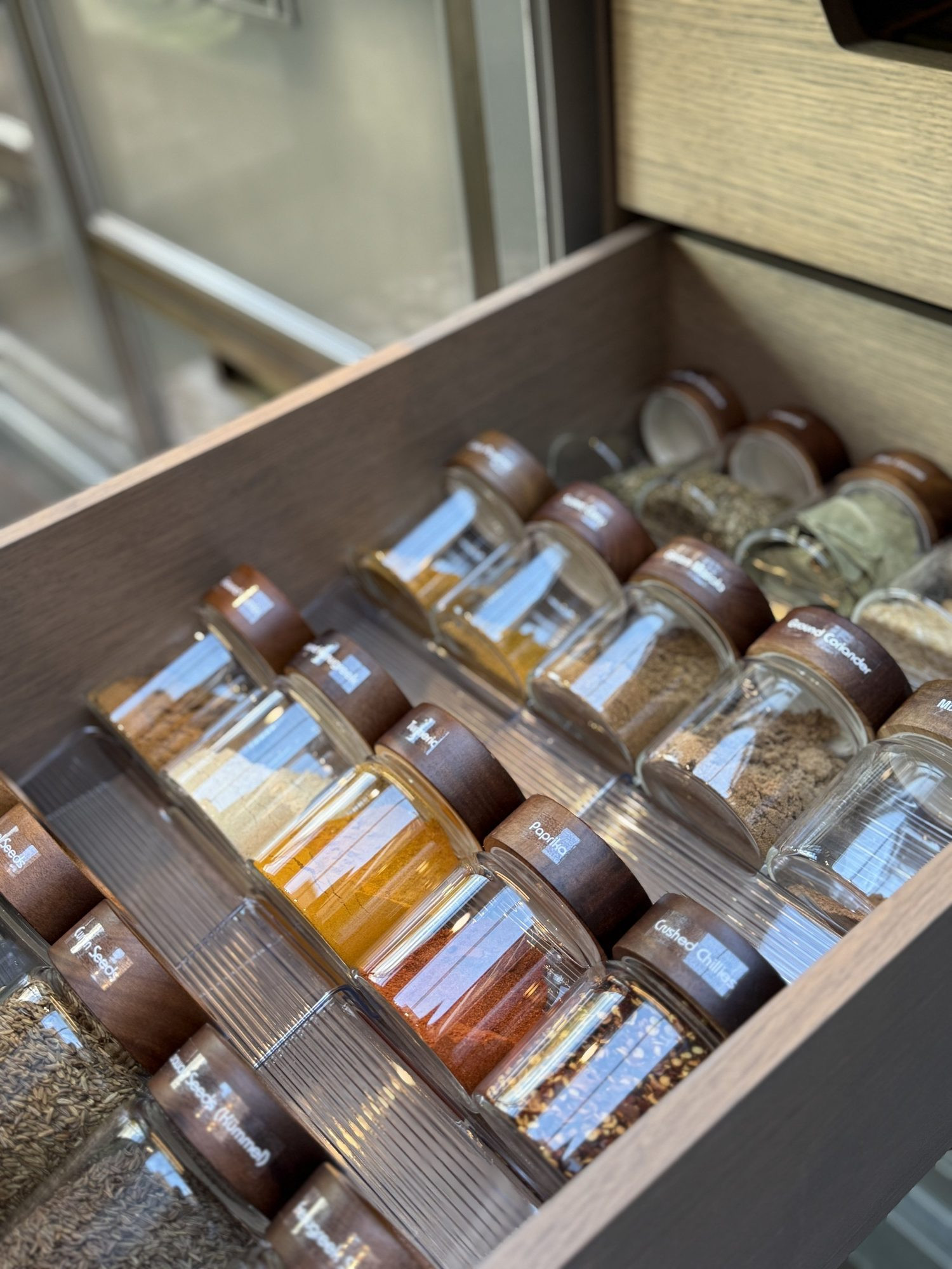 Spice jars laid in rows in a kitchen drawer.